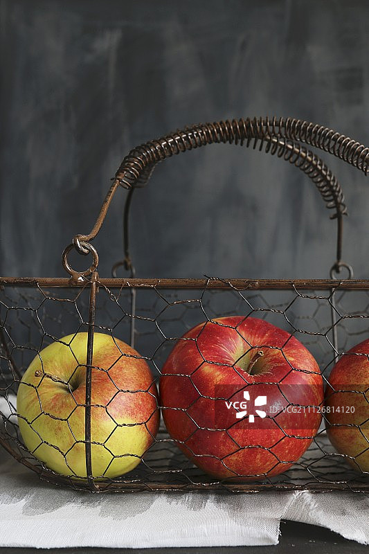 灰色背景下，老式铁丝篮子里的苹果图片素材