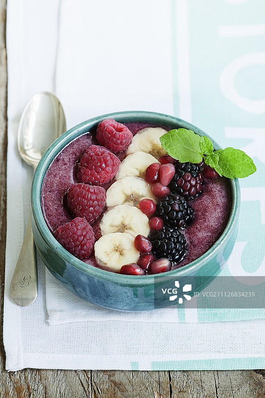 由树莓、黑莓、香蕉和草莓制成的冰沙碗，用树莓、香蕉、黑莓和石榴籽装饰图片素材
