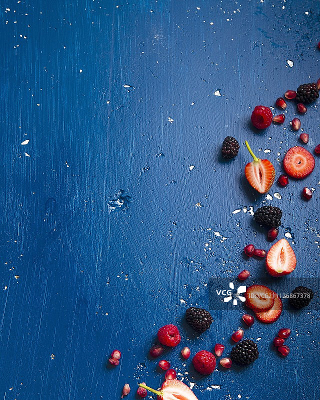 蓝色背景上的各种浆果和石榴籽图片素材
