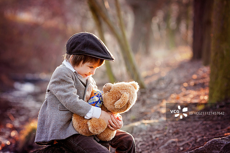 可爱的小男孩和他的泰迪熊朋友在公园里图片素材