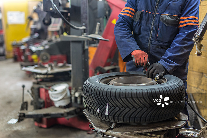 专业的汽车修理工在汽车修理服务中更换轮胎。图片素材
