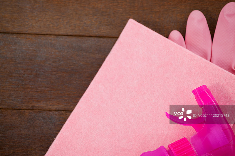 特写的粉红色喷瓶，海绵和手套在木地板上图片素材