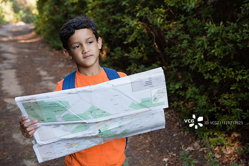 男孩拿着地图，在森林里看着远方图片素材