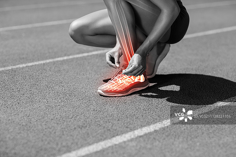 女运动员在阳光明媚的日子里在跑道上系鞋带图片素材