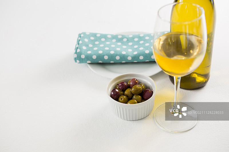 特写腌制橄榄与玻璃和一瓶葡萄酒在白色的背景图片素材