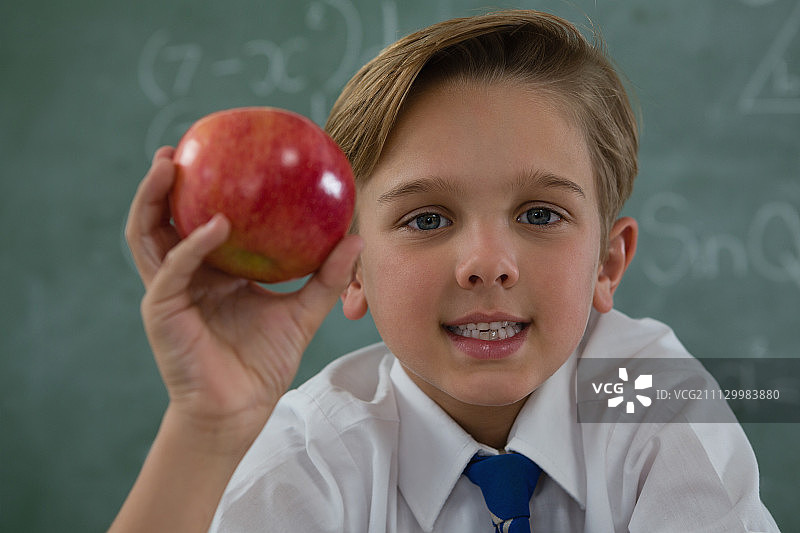 一个男生在黑板上拿着红苹果的肖像图片素材