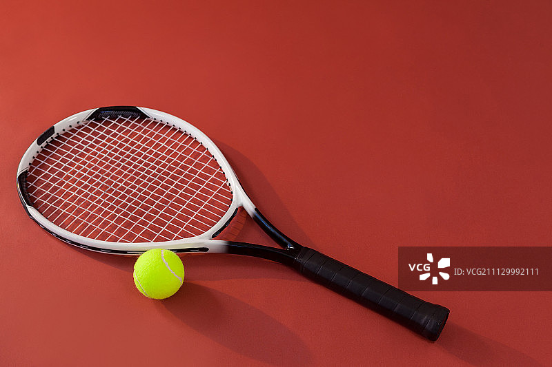 高角度的网球拍和荧光黄色球在栗色的背景图片素材