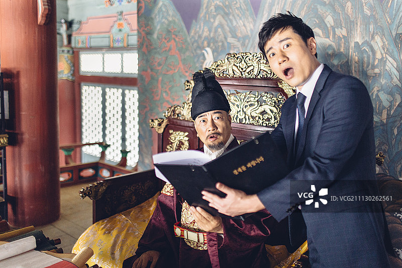 惊讶的现代年轻商人显示剪贴板的高级男子在韩国国王服装图片素材