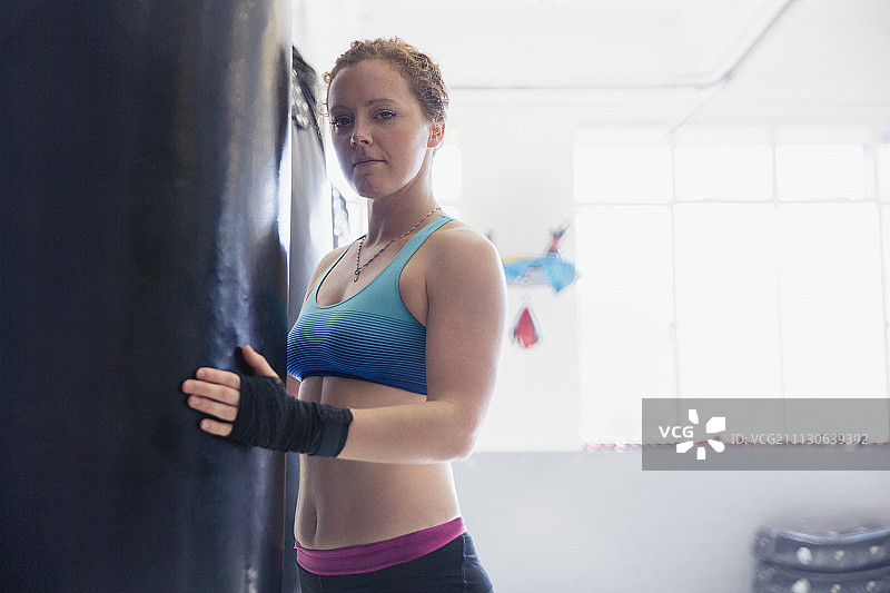肖像自信，坚强的女拳击手在拳击袋在健身房图片素材
