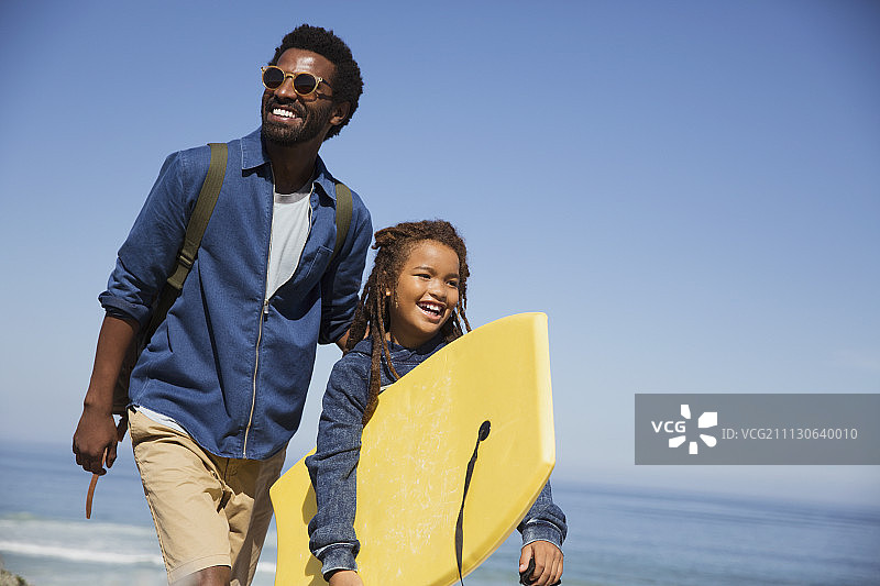 微笑的父亲和女儿与冲浪板在阳光明媚的夏季海洋海滩图片素材