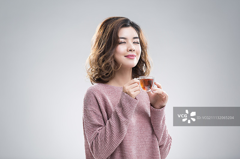快乐的年轻女子喝红茶图片素材