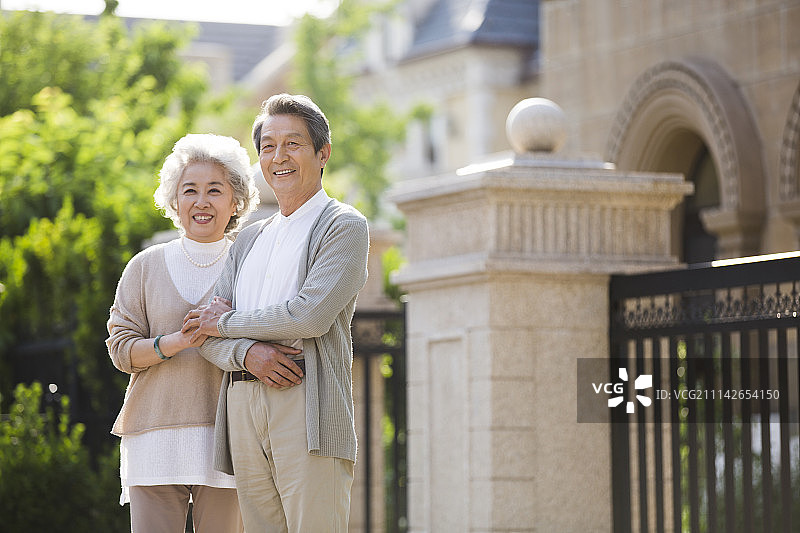 快乐的老年夫妇站在别墅前眺望远方图片素材