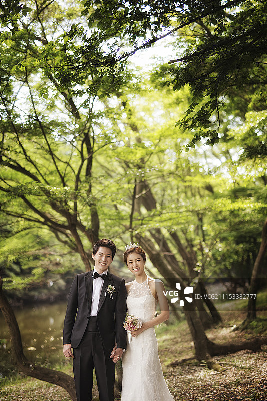 幸福的新娘和新郎牵手在森林里图片素材