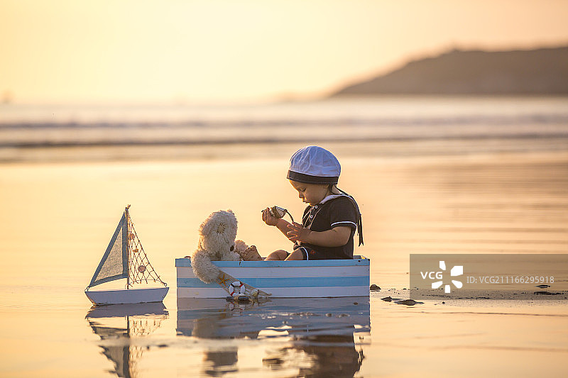 小男孩在海滩上玩水手在夏天日落图片素材