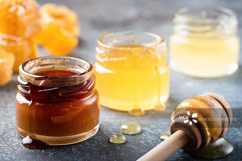 蜂蜜在罐子与木制蜂蜜勺，液体蜂蜜图片素材