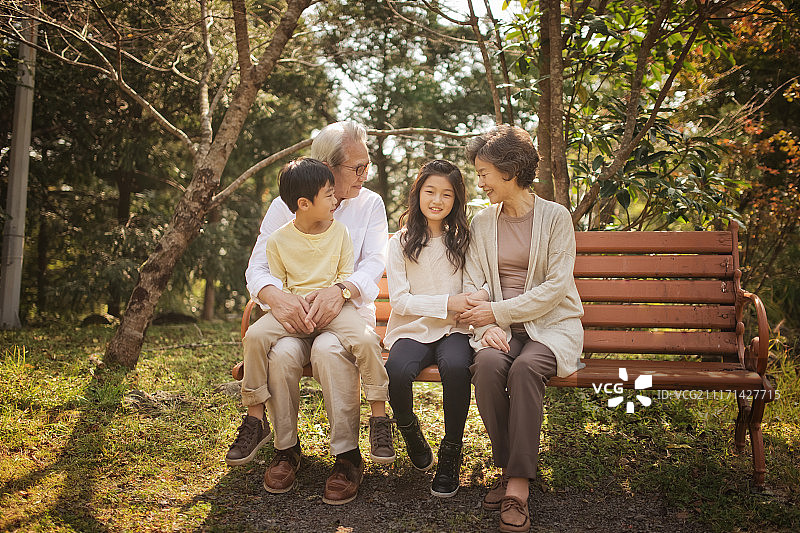 祖父母和孙子坐在公园长椅上的照片图片素材