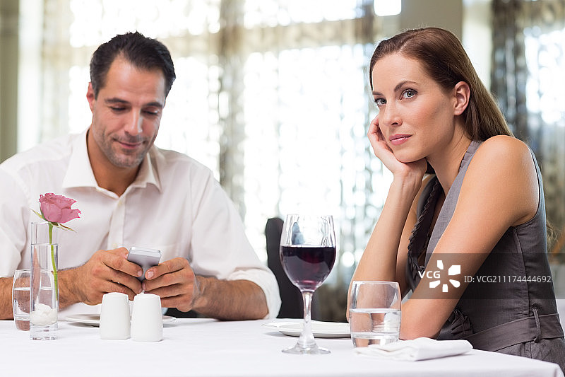 情侣们拿着酒杯和手机在餐厅用餐图片素材