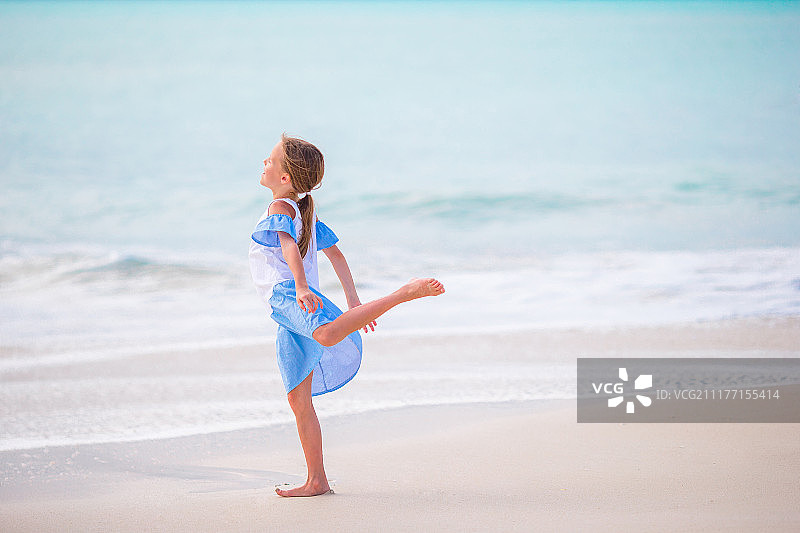 可爱的小女孩在海滩上快乐的女孩享受暑假背景蓝色的天空和图片素材