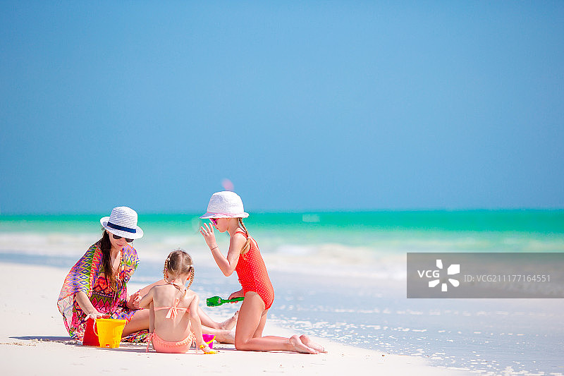 妈妈和小女儿们在热带海滩上建造沙堡图片素材