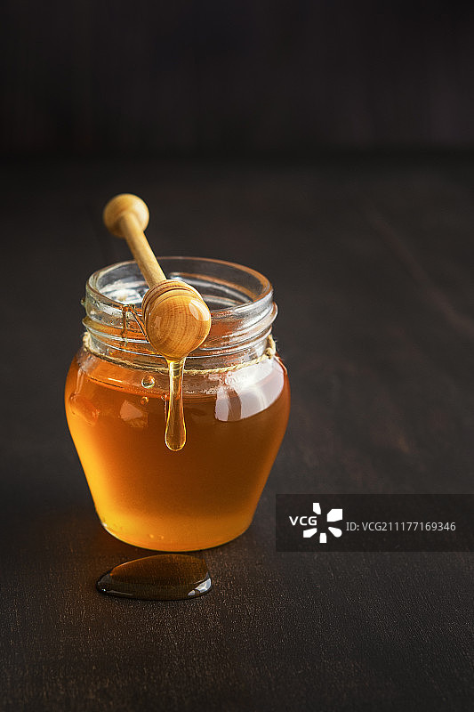蜂蜜在一个玻璃罐与蜂蜜勺在乡村木桌子背景拷贝空间图片素材
