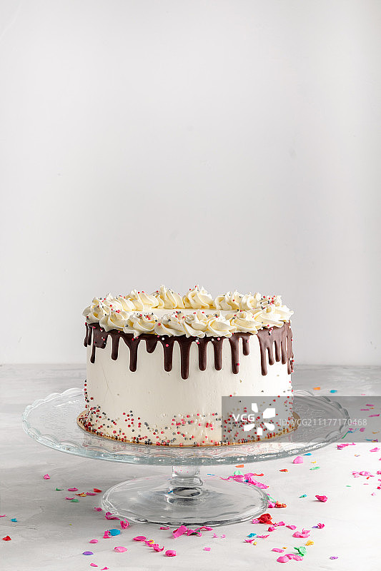 简单的生日蛋糕与巧克力甘纳许和点缀在一个白色的背景与派对图片素材