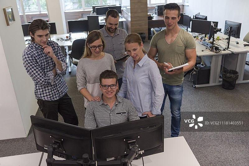 一群年轻的创业人士站在办公桌前完成日常工作图片素材
