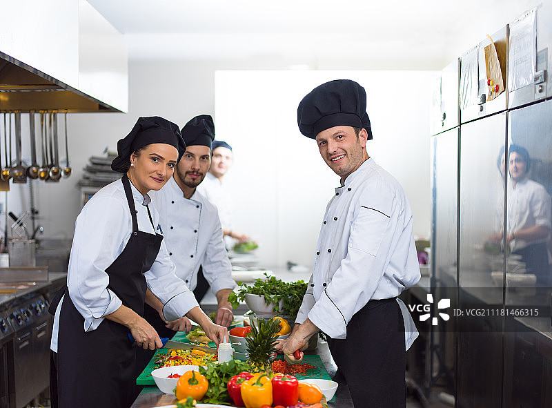 专业团队厨师和厨师在繁忙的酒店或餐厅厨房准备饭菜。团队厨师和厨师准备饭菜图片素材
