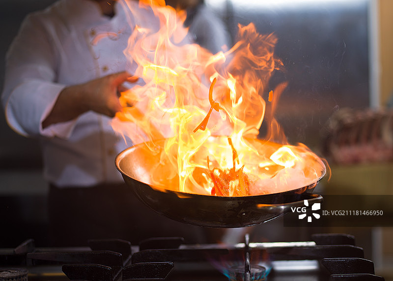 厨师长在餐厅厨房烹饪和做火苗。厨师在做食物上的火焰图片素材