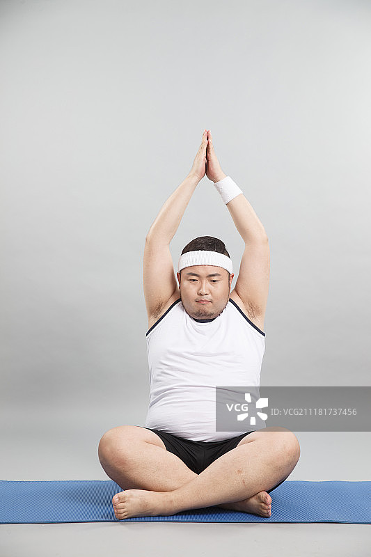 肥胖的青年男人在做瑜伽图片素材