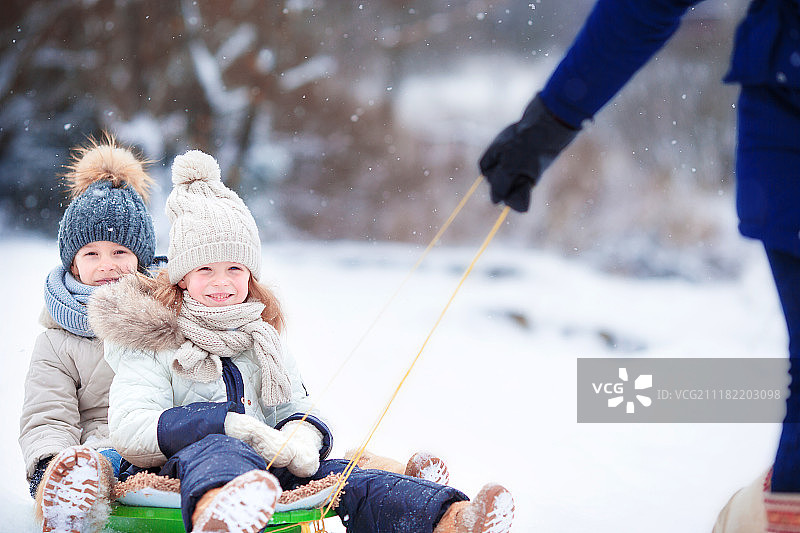 乘坐雪橇的小女孩乘坐雪橇的孩子们在户外滑雪家庭度假中玩耍图片素材
