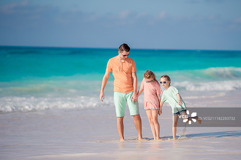 父亲和两个小女儿站在沙滩上图片素材