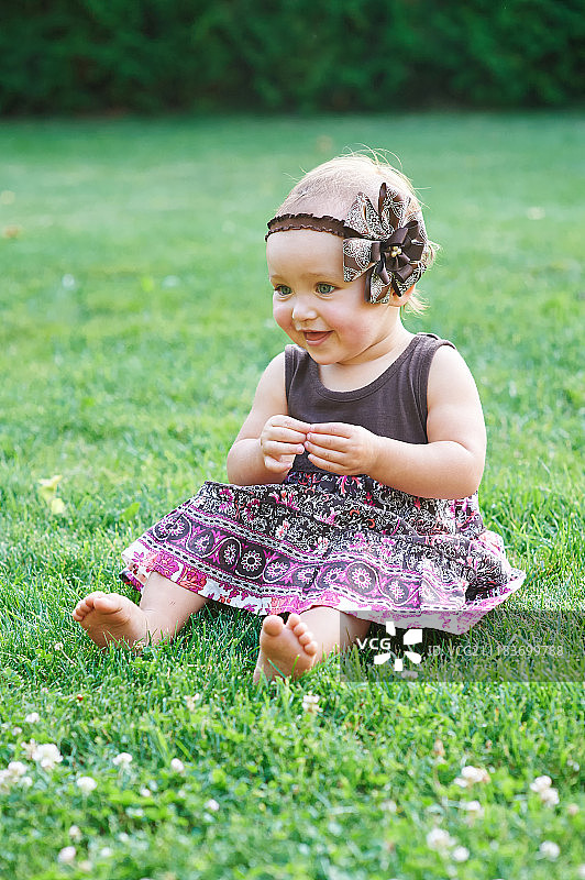 小女孩坐在草坪上的绿草上图片素材
