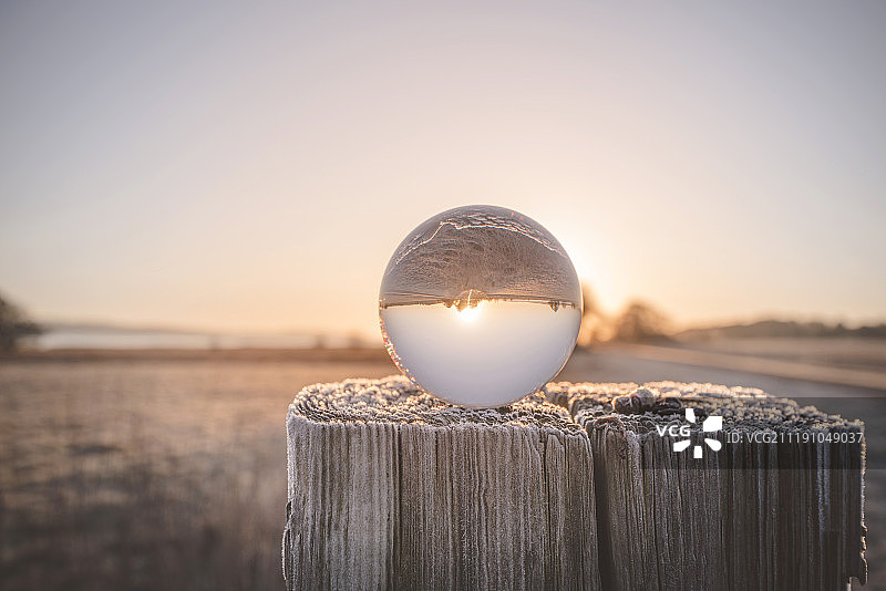 太阳升起时木柱上的玻璃球图片素材