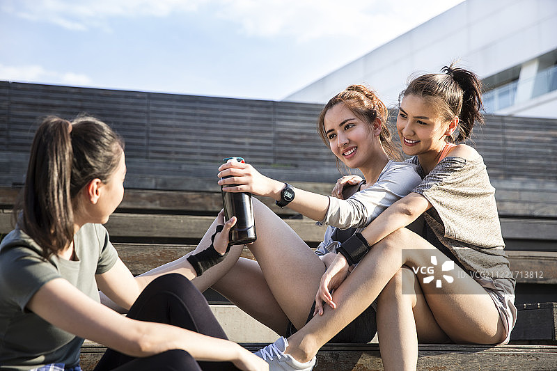 三个青年女子在户外运动后休息喝水图片素材