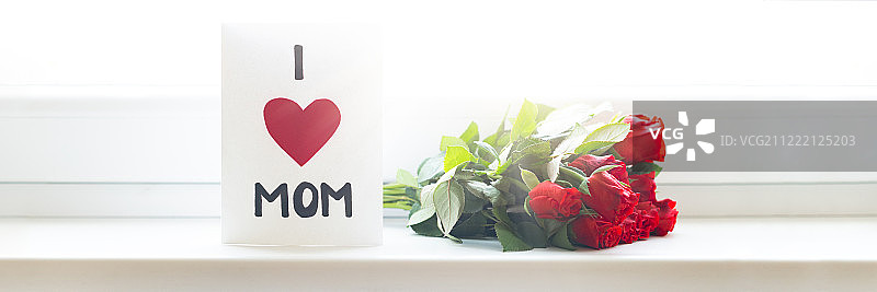 母亲节快乐或生日横幅自制贺卡和窗户上的一束红玫瑰图片素材