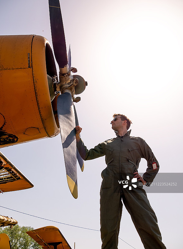一个英俊的年轻飞行员站在螺旋桨旁边图片素材