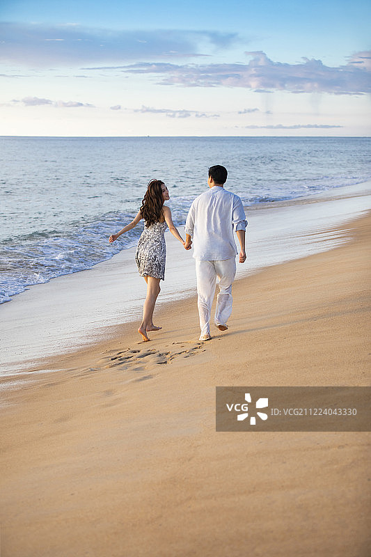 快乐的年轻夫妇在沙滩奔跑图片素材