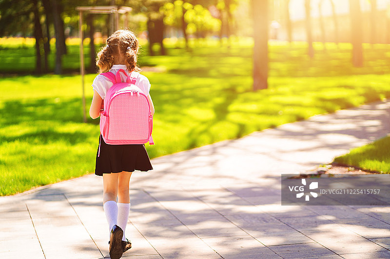 美丽的小女孩背着背包在公园散步准备回学校，后视镜，秋天图片素材