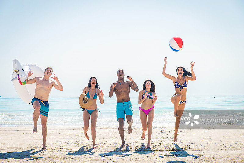 一群快乐的年轻朋友在夏天的海滩上跳跃图片素材