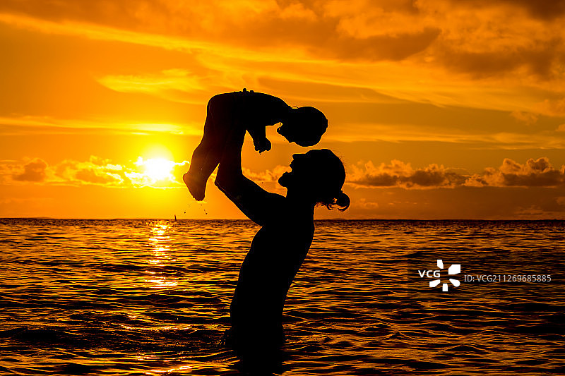 在日落的海洋背景下，父亲接儿子，小卡斯诺耶尔，毛里求斯图片素材