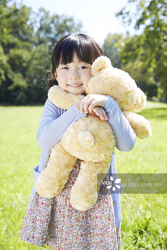小女孩在公园里拥抱泰迪熊的照片图片素材