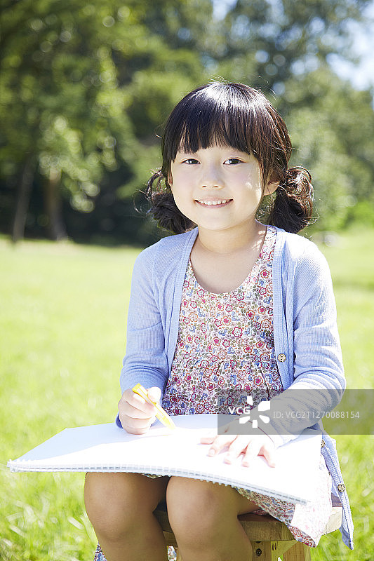 小女孩在公园素描簿上画画的照片图片素材
