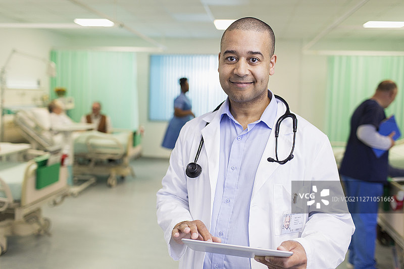 描绘自信的男医生在病房里用平板电脑查房图片素材