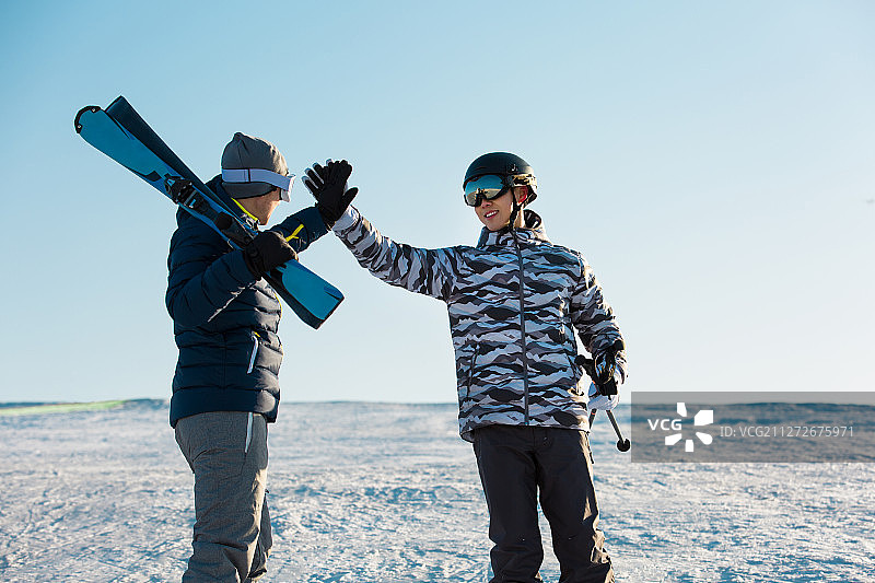 两个青年男子在户外滑雪场击掌庆祝成功图片素材