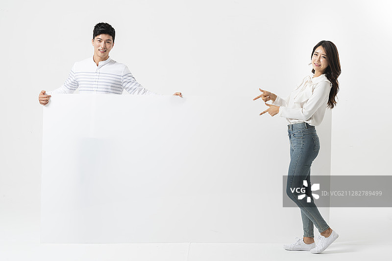 男人站在后面，女人站在白色空白横幅前，用姿势拍照图片素材