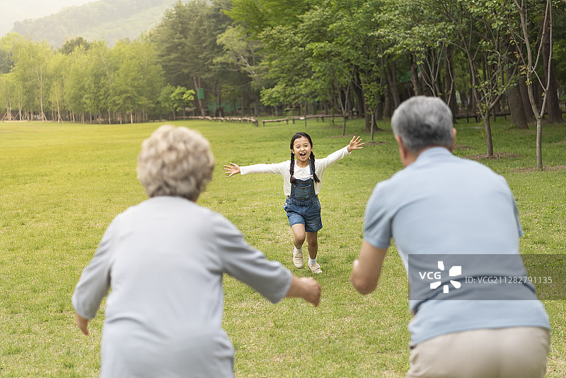 孙女在森林的草地上向祖父母跑去的照片图片素材