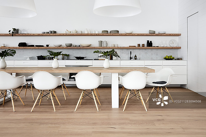 木制架子下的白色厨房柜台和带贝壳椅的餐桌图片素材