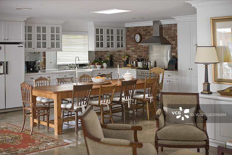 厨房配有白色橱柜和实木餐桌后的砖墙图片素材