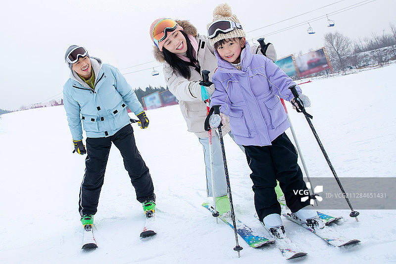 滑雪场上教女儿滑雪的一家三口图片素材