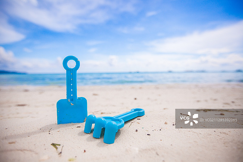 蓝色的特写，塑料铲和耙子-儿童的玩具-在海滩上图片素材